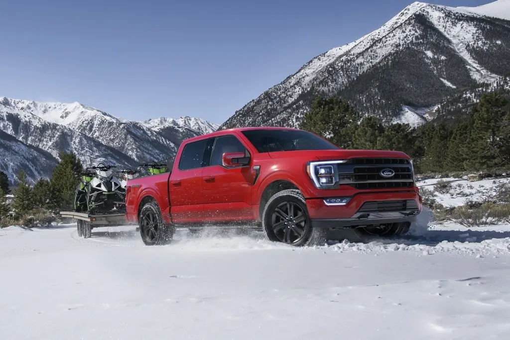 The 2023 Ford F-150 driving on snow towing snowmobiles