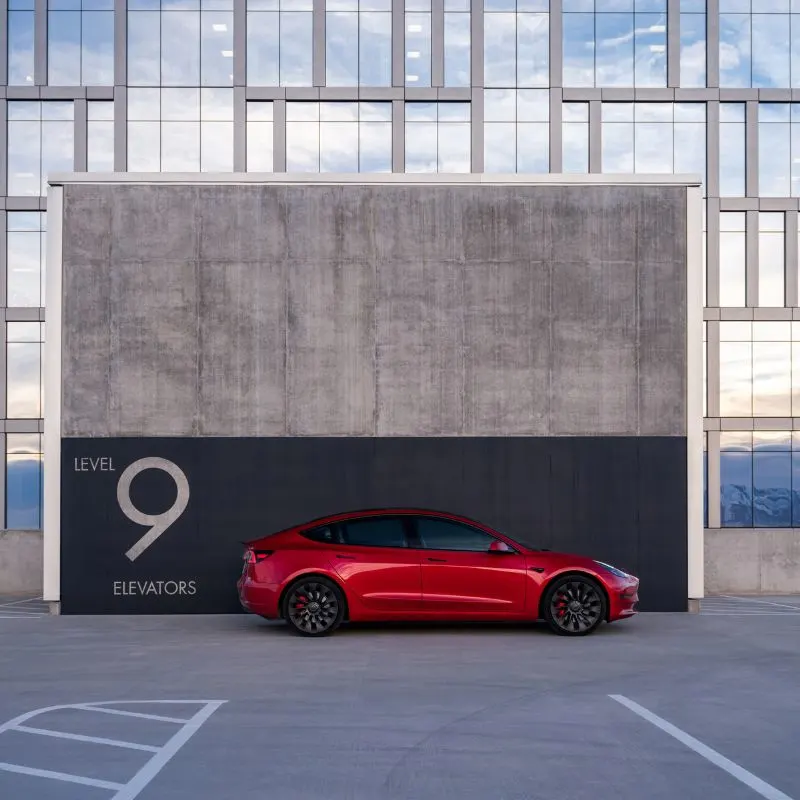 Tesla Model 3 - Red ev parked in front of a building